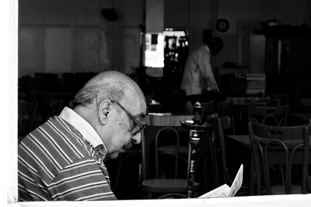 Reading a paper in his regular cafe in Damascus