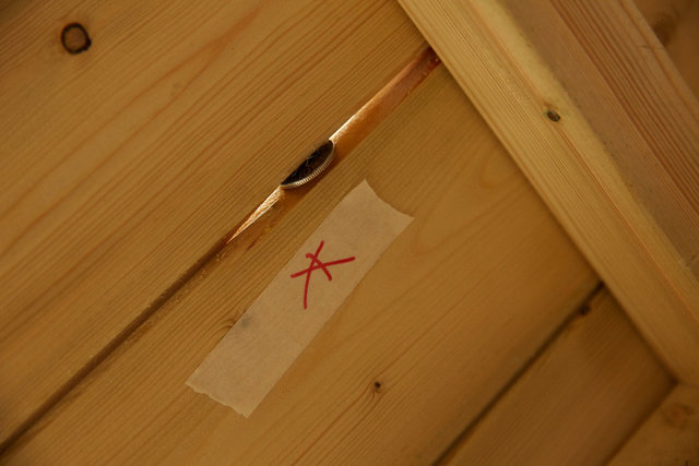 Photo showing gap in tongue and groove of front panel of shed with 10 pence coin inserted to show size of gap