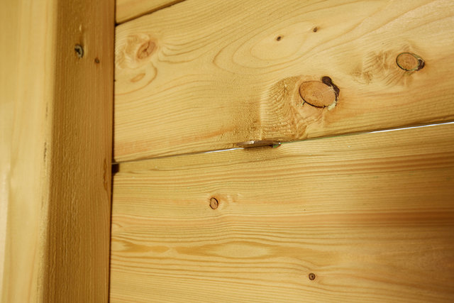 Photo showing gap in tongue and groove of back panel of shed with 50 pence coin inserted to show size of gap