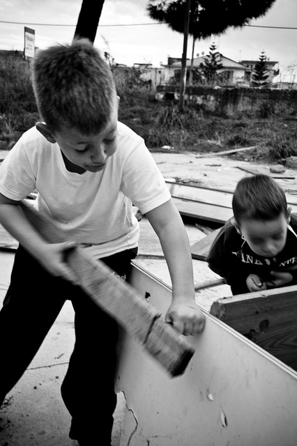 Bambini piccolissimi che giocano a costruire una capanna con scarti di mobili abbandonati nel parco