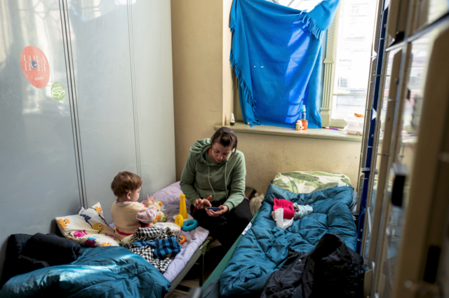 Una donna con suo figlio si riposa in un corridoio della stazione - Stazione dei treni di Przemyśl.png