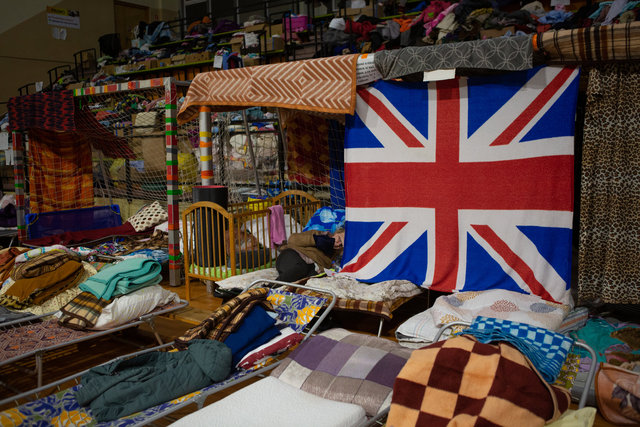 Una donna cerca uno spazio di intimità ricavato grazie a teli appesi nella grande Palestra riadibita a centro di accoglienza da parte del Polish Humanitarian Action – confine di Zosin (3 ore di auto da Leopoli)..jpg