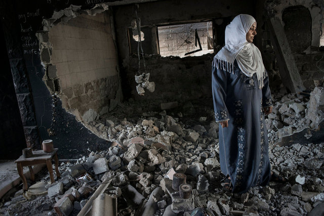 A woman in her destroyed house with some unexploded bombs. 