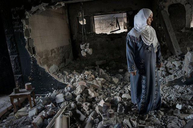 A woman in her destroyed house with some unexploded bombs.