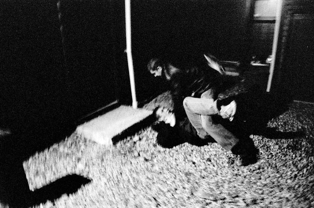 A fight between two friends in a driveway, just outside of a party.