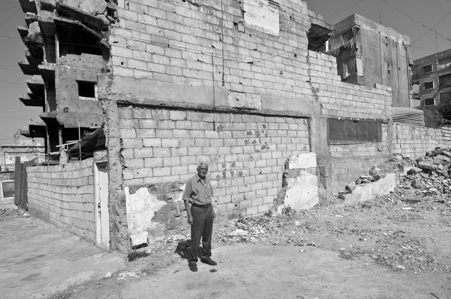 A man who stands where once his house stood