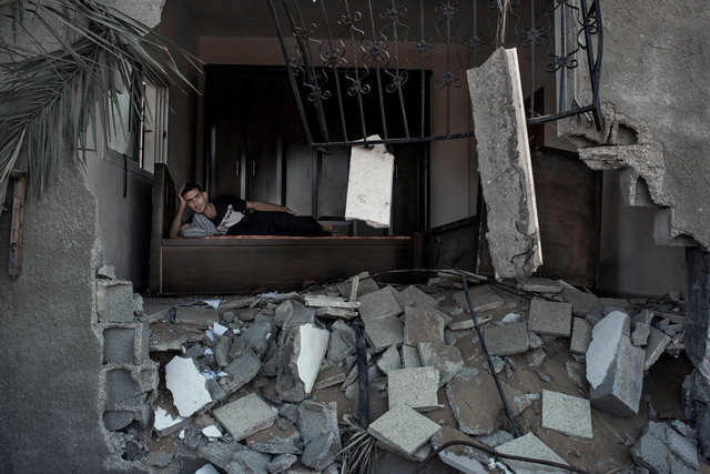 Walid Rouck , 24, amidst the rubbles of his neighbour's house in Khuzaa, Gaza Strip 