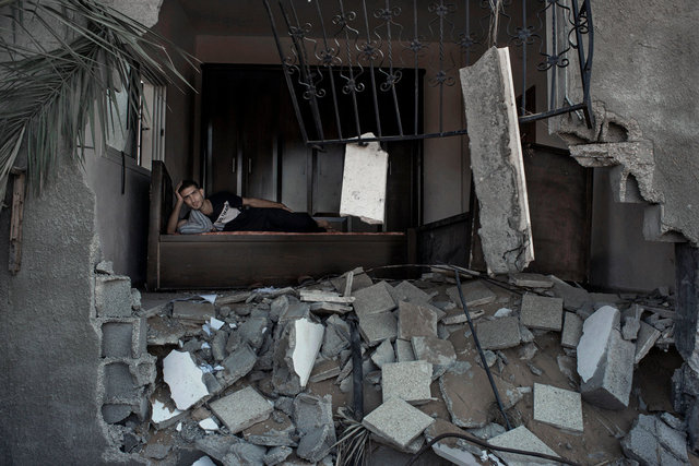Walid Rouck , 24, amidst the rubbles of his neighbour's house in Khuzaa, Gaza Strip