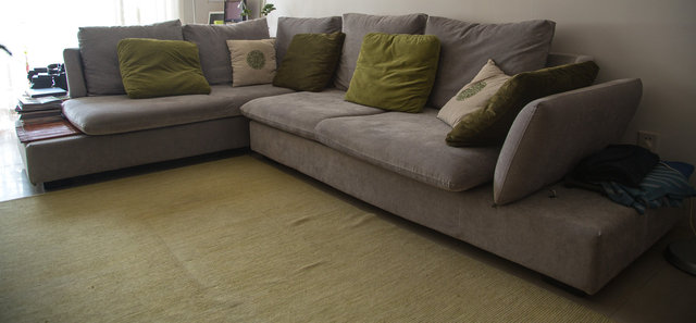 Big L-shaped grey sofa with green pillows