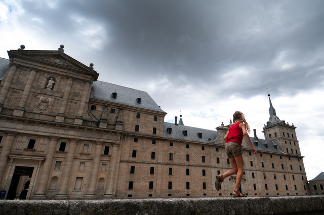 Girl in red running past the El Escorial Palace 