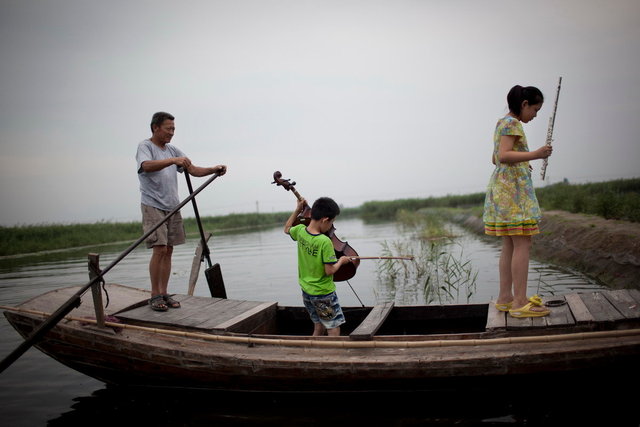 河北安新县，接受音乐培训的孩子们提着各自的乐器走下船.JPG